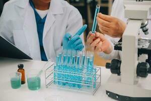 Scientist or medical in lab coat working in biotechnological laboratory, Microscope equipment for research with mixing reagents in glass flask in clinical laboratory. photo