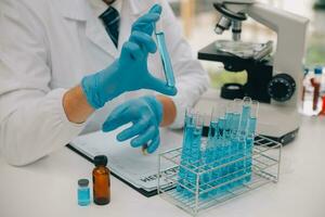 Scientist or medical in lab coat working in biotechnological laboratory, Microscope equipment for research with mixing reagents in glass flask in clinical laboratory. photo