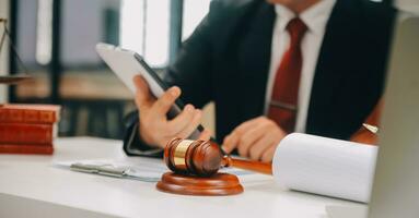 Business and lawyers discussing contract papers with brass scale on desk in office. Law, legal services, advice, justice and law concept picture with film grain effect photo