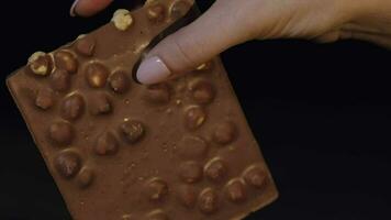 Black chocolate block bar in woman's hand close-up video