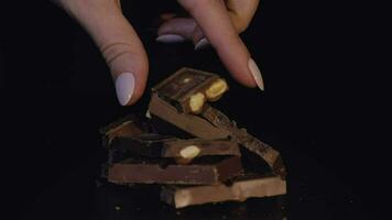 twee vrouw vingers duurt een stuk van chocola bar. langzaam beweging video