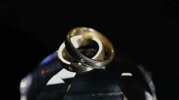 Boda anillos acostado en cristal brillante con ligero cerca arriba macro video