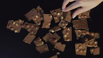 Woman hand takes piece of chocolate from a bunch of chocolate pieces video