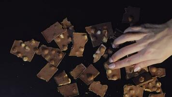 Woman hand takes piece of chocolate from a bunch of chocolate pieces video
