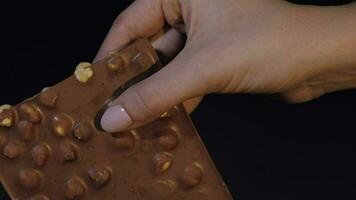 Black chocolate block bar in woman's hand close-up video