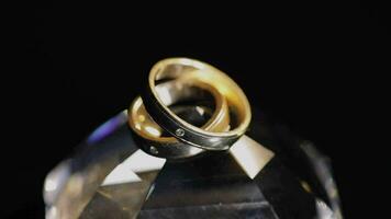 Boda anillos acostado en cristal brillante con ligero cerca arriba macro video