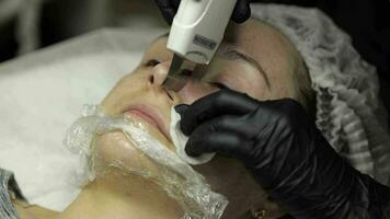 Cosmetologist make ultrasonic face cleaning on woman face in beauty clinic salon video