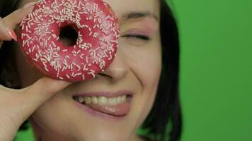 contento hermosa joven niña posando y teniendo divertido con rosquilla. croma llave video