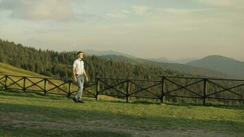 Young man walking neat fence in the park. Slow motion video