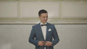 Handsome groom fixes his jacket. Wedding day. Slow motion video