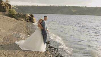 Jungvermählten Stand auf das Flussufer. das Braut Umarmungen das Bräutigam. Hochzeit Paar video