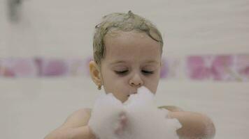 aantrekkelijk drie jaren oud meisje duurt een bad. schattig blond kind video