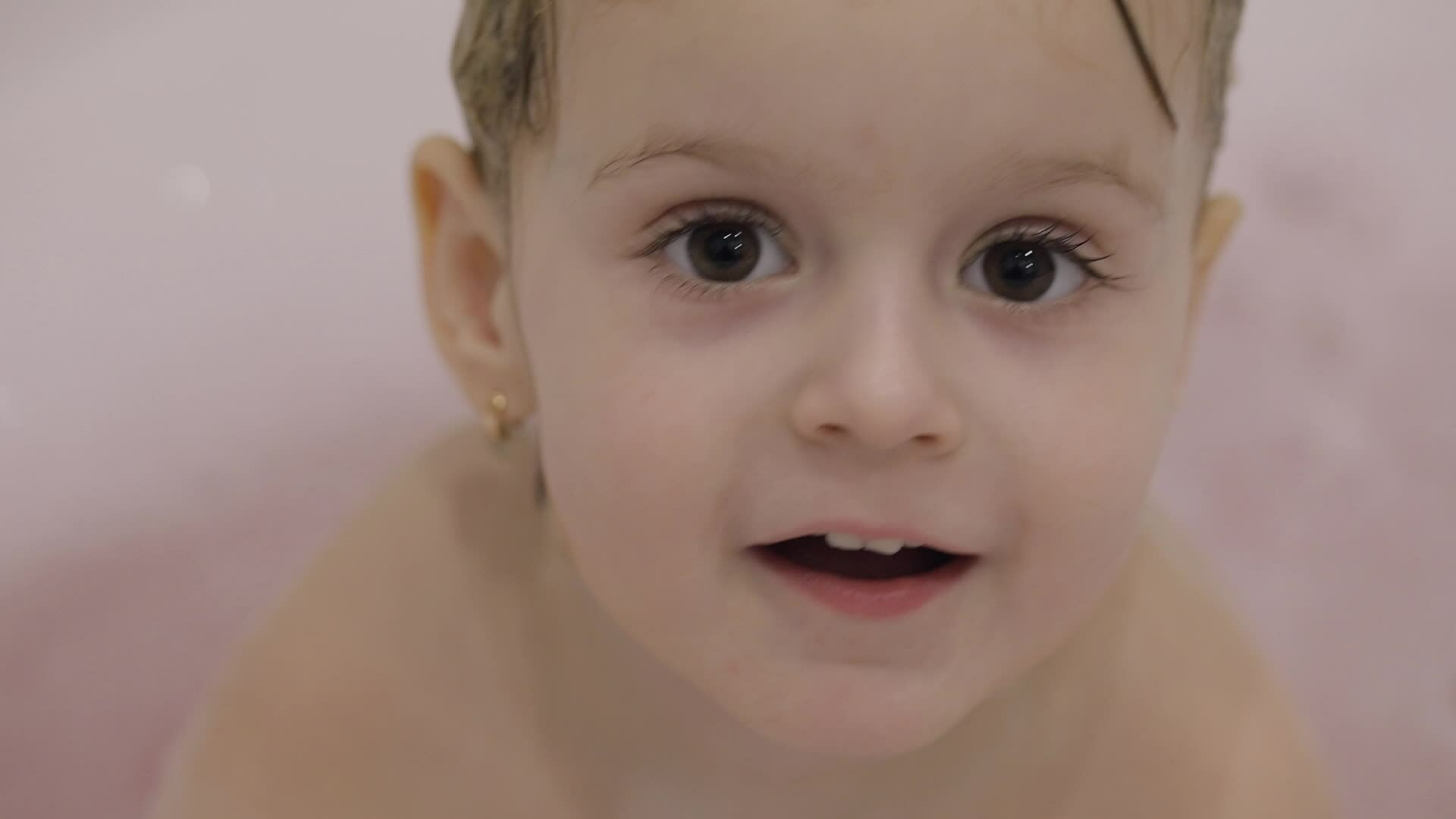 Attractive three years old girl takes a bath. Cute blonde child
