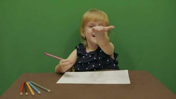 niña sentado a el mesa. educación proceso. linda niña sonriente. croma llave video