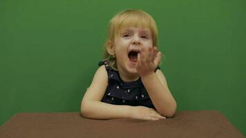 niña sentado a el mesa. educación proceso. linda niña sonriente. croma llave video