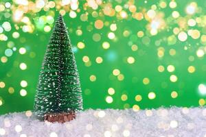 Snow-covered Christmas tree on snow and green background with bokeh. Christmas banner concept, card with mark for copy photo