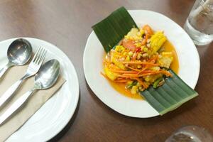 Thai Papaya Salad with Corn serve on banana leaf decoration on plate  on wooden table photo