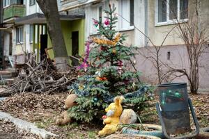 Christmas tree with toys near the house in the ruined city in Ukraine photo