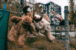 soft toys are dried after washing against the background of a burnt-out building in Mariupol photo