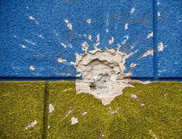 explosion damaged blue yellow house wall war in Ukraine photo