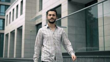 attractive white young man walks forward along a modern business building video