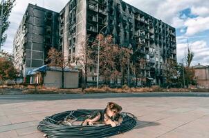 mongrel puppy basks in the sun against the background of a burnt-out house in Mariupol photo