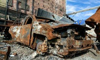 burnt car on the street of the ruined city photo