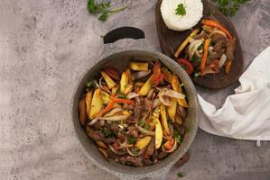 Dish named Lomo saltado, seen from above in a casserole and a wooden plate. photo