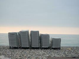 Stacked plastic sun loungers on the beach. Sunbeds in bad weather. Resort in off season. photo