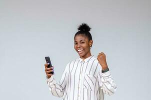 young pretty african lady feeling overexcited about what she saw on her sell phone photo