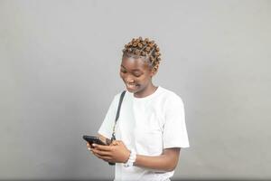 beautiful young african lady excited and rejoices while looking at her phone photo