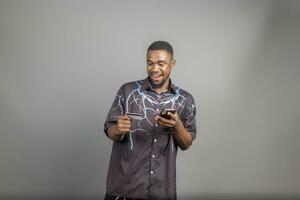 handsome young black man using his credit card and phone to shop online, banking online concepts photo