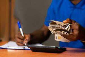 african man holding come money and doing paperwork also photo