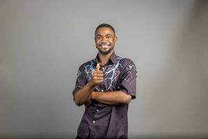 Smiling man posing with arms crossed on white background and did thumbs up photo