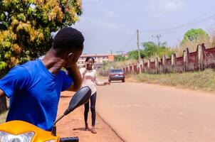 joven hermoso africano motorista haciendo llamadas mientras esperando para su cliente a llegar foto