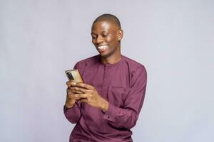 Portrait of cheerful African American student typing a message on smart phone, sharing success with his friends via social networks over white background photo