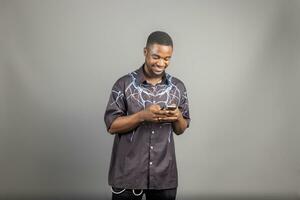 Attractive African American man texting on his phone isolated over grey photo