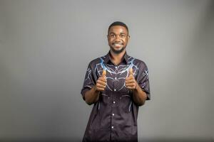 young man smiling broadly looking happy, positive, confident and successful, with both thumbs up photo