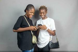 beautiful young african women feeling excited and happy while looking at their mobile phones photo