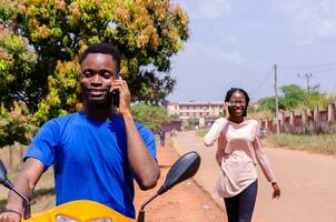 handsome african biker calling his customer he have arrived while they are smiling photo