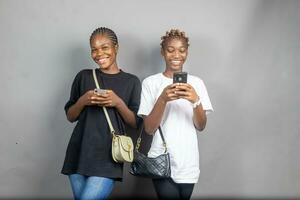 two beautiful young black women viewing content together on a phone feeling excited photo