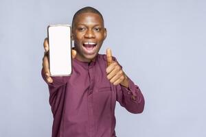 Excited black guy in casual showing cellphone with empty screen on white studio background, space for website or mobile app design. photo