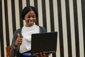 beautiful african lady feeling overexcited as she points to her laptop photo