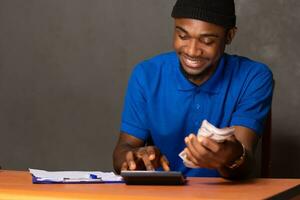 sonriente joven negro hombre haciendo algunos financiero cálculos foto