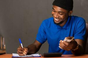 happy young black man doing some financial calculations photo