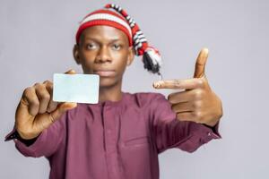 african man wearing african attire dress holding id card pointing at the mock up . selective focus photo