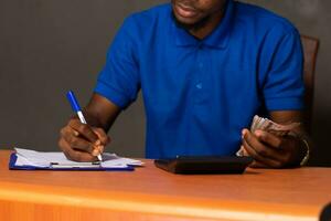 black young man doing some calculations, holding some money photo