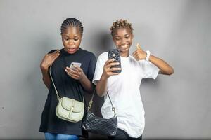 two beautiful young black women viewing content together on a phone feeling excited photo