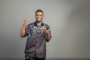 Cheerful millennial black man in casual using modern smart phone, checking social media, looking at copy space for mobile application photo