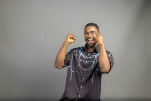 Overexcited young black guy raising fist up on white background, celebrating success. Happy African millennial man sharing positive emotions, copy space, empty space photo